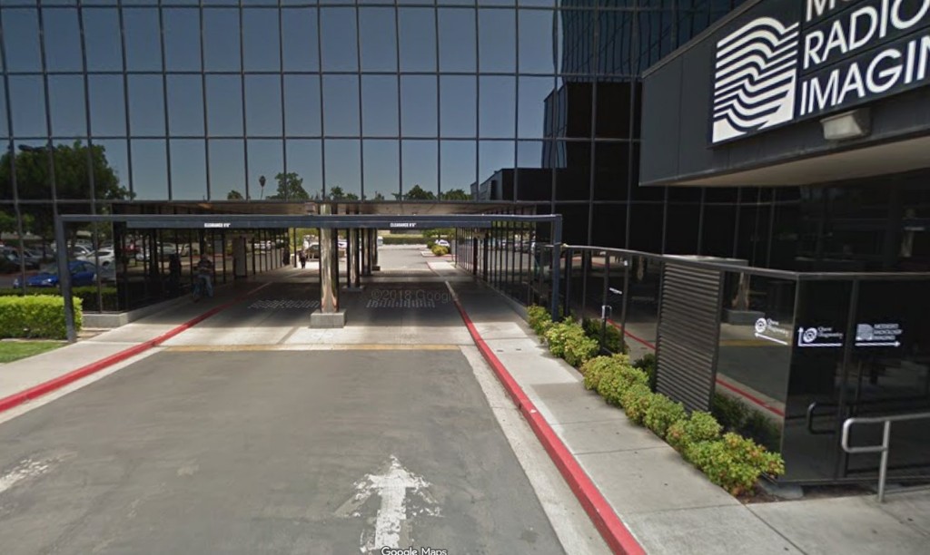 The main driveway at 1524 McHenry Ave, running under the glass building past the Modesto Radiology Imaging sign, with red curbs on both sides.